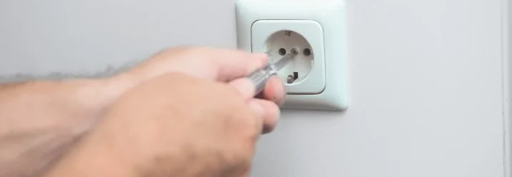 Hände schrauben Steckdose mit Schraubenzieher an